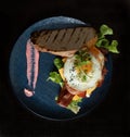 Fried egg bacon cheese lettuce bread roll breakfast served on blue plate Royalty Free Stock Photo