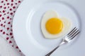 Fried egg in a heart shape in a white plate