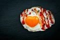 Fried egg with heart shaped yolk, spices and ketchup