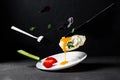 Fried egg levitation. Dark food photo. A chicken egg with liquid yolk, leaves of basil, dill, cucumber falls on a white plate.