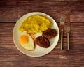 Fried egg, mashed potatoes and two meat patties in a round plate on a wooden table Royalty Free Stock Photo