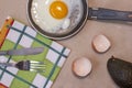 Fried egg on the pan, egg shells, dish towel, knife and fork, avocado Royalty Free Stock Photo