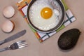 Fried egg on the pan, fork and knife, avocado, egg shell, dish towel. Royalty Free Stock Photo