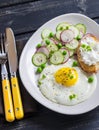 Fried egg, salad with cucumbers, radishes and green peas, toast with feta cheese on a light ceramic plate on dark wooden backgroun Royalty Free Stock Photo