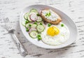 Fried egg, salad with cucumbers, radishes and green peas, toast with feta cheese on a light ceramic plate on wooden background. Royalty Free Stock Photo