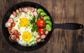 Fried egg and sausage in the pan on wooden background