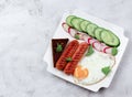 Fried egg and sausages with sliced vegetables and toast on a white rectangular plate on a light gray background Royalty Free Stock Photo