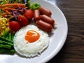 Fried egg with sausages and vegetables in the white plate