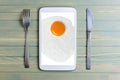 Fried egg on the tablet screen. Cutlery - knife and fork. Wooden background Royalty Free Stock Photo