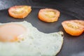 Fried egg with tomatoes in a cast-iron frying pan on a wooden table Royalty Free Stock Photo