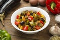 Fried eggplants, potatoes and bell peppers on a rustic wooden table with ingredients.