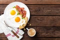 Fried eggs, bacon and italian ciabatta bread on white plate. Cup of coffee. Breakfast. Top view. Wooden background Royalty Free Stock Photo