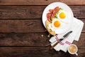 Fried eggs, bacon and italian ciabatta bread on white plate. Cup of coffee. Breakfast. Top view. Wooden background Royalty Free Stock Photo