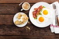 Fried eggs, bacon and italian ciabatta bread on white plate. Cup of coffee. Breakfast. Top view. Wooden background Royalty Free Stock Photo