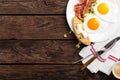 Fried eggs, bacon and italian ciabatta bread on white plate. Cup of coffee. Breakfast. Top view. Wooden background Royalty Free Stock Photo