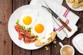 Fried eggs, bacon and italian ciabatta bread on white plate. Cup of coffee. Breakfast. Top view. Wooden background Royalty Free Stock Photo