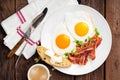 Fried eggs, bacon and italian ciabatta bread on white plate. Cup of coffee. Breakfast. Top view. Wooden background Royalty Free Stock Photo