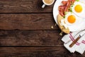 Fried eggs, bacon and italian ciabatta bread on white plate. Cup of coffee. Breakfast. Top view. Wooden background Royalty Free Stock Photo