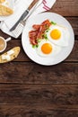 Fried eggs, bacon and italian ciabatta bread on white plate. Cup of coffee. Breakfast. Top view. Wooden background Royalty Free Stock Photo