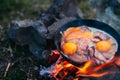 Fried eggs with bacon in a pan in the forest. Food at the camp. Fried egg with bacon on fire. Royalty Free Stock Photo