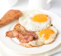 Fried eggs with bacon on a plate on a napkin on a white background