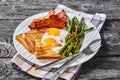 Fried eggs, bacon, toast, asparagus on a plate