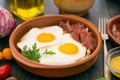 Fried eggs in a ceramic cup with spanish jamon for breakfast on a dark wooden background Royalty Free Stock Photo