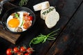Fried eggs with cherry tomatoe and bread for breakfast in cast iron frying pan, on old dark  wooden table background , with space Royalty Free Stock Photo