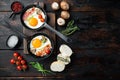 Fried eggs with cherry tomatoe and bread for breakfast in cast iron frying pan  on old dark wooden table background  top view Royalty Free Stock Photo