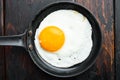 Fried eggs with cherry tomatoe and bread for breakfast in cast iron frying pan, on old dark  wooden table background, top view Royalty Free Stock Photo