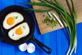 fried eggs, crispy toast and spring onion on blue wooden table