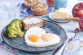 Fried eggs in the form of heart. On a dark plate with broccoli and toast. Blue cup with tea, butter for breakfast and cupcakes. On Royalty Free Stock Photo