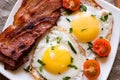 Fried eggs fried bacon and cherry tomatoes sprinkled with parsley Royalty Free Stock Photo