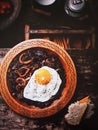 Fried eggs in frying pan with arugula leaves, salt and pepper for breakfast on black wooden background. Royalty Free Stock Photo