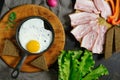 Fried eggs in a frying pan, smoked bacon, rye bread, lettuce leaves, top view. Royalty Free Stock Photo