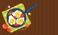 Fried eggs in a frying pan with vegetables, tomatoes, peppers. Healthy brunch with fresh homemade meal on a wooden table. Royalty Free Stock Photo