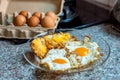 Fried eggs in a glass pan with fresh raw eggs in background Royalty Free Stock Photo