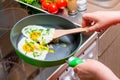 Fried eggs on a griddle, hands with a wooden spatula