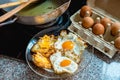 Fried eggs in kitchen with fresh raw egg and a pan in background Royalty Free Stock Photo