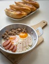 Fried eggs in a pan with meat on the wooden plate. The famous breakfast with Banh Mi - Vietnamese bun with meat Royalty Free Stock Photo