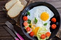 Fried eggs in pan with tomato, bread, pepper and parsley