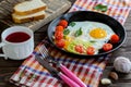 Fried eggs in pan with tomato, bread, pepper and parsley