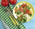 Fried eggs on a plate green onions, bread appetizer tomato, knife fork, blue wooden background, towel, parsley