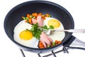 Fried eggs with sausage and vegetables in frying pan on white ba Royalty Free Stock Photo