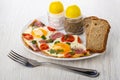 Fried eggs with sausages, tomato, salt and pepper, bread in plat