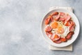 Fried eggs sausages and tomatoes on a plate on the table. Rich homemade Breakfast. Gray concrete background. Copy space Royalty Free Stock Photo