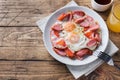Fried eggs sausages and tomatoes on a plate on the table. Rich homemade Breakfast. Wooden background. Copy space Royalty Free Stock Photo