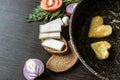 Fried eggs in the shape of a heart in a frying pan, near which lay bread slices, lard salo, red onion, tomato, garlic and dill. Royalty Free Stock Photo