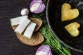 Fried eggs in the shape of a heart in a frying pan, near which lay bread slices, lard salo, red onion, tomato, garlic and dill Royalty Free Stock Photo