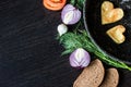 Fried eggs in the shape of a heart in a frying pan, near which lay bread slices, red onion, tomato, garlic and dill Royalty Free Stock Photo